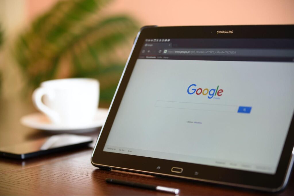 Потребител се готви да въведе заявка с ключова дума в полето за търсене в Google на своя таблет докато пие кафе сутрин