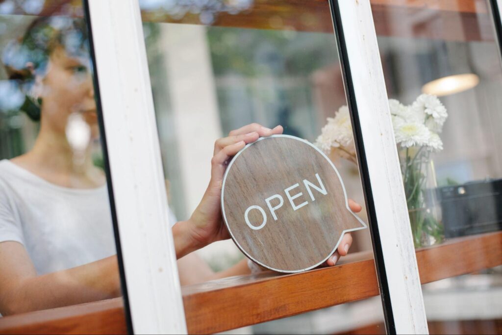 Управител на магазин слага табела "отворено" в допълнение на локалната оптимизация за бизнеса си
