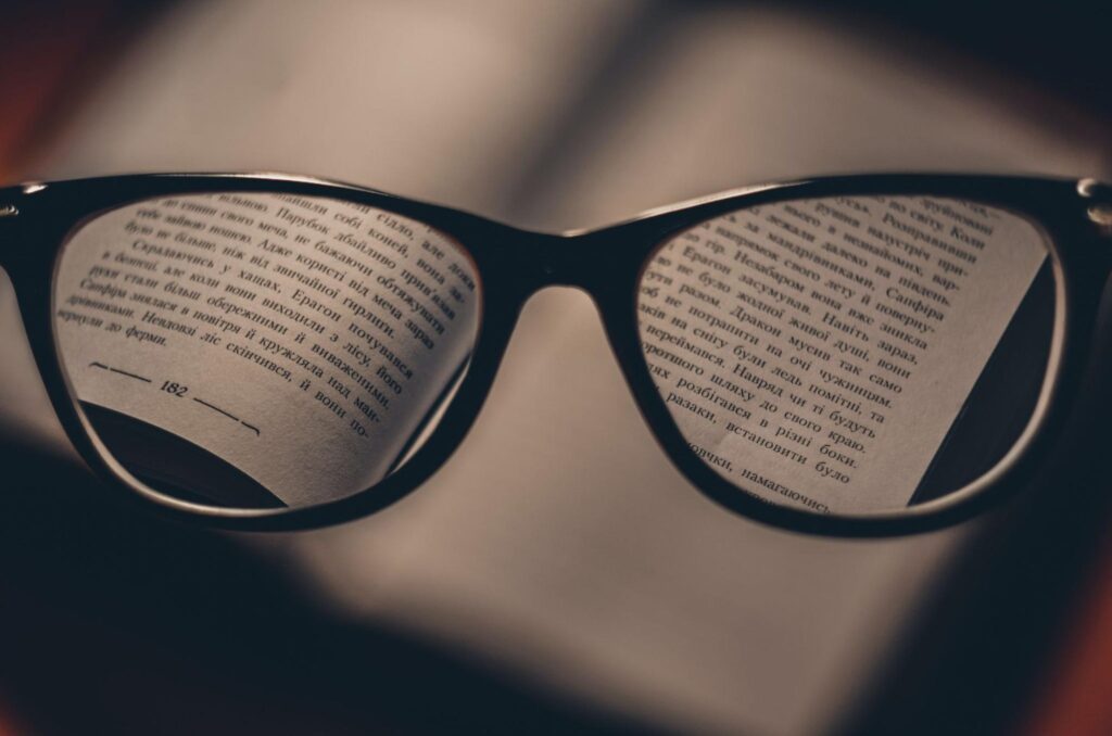Фокусиран текст от книга през призмата на очила по време на редакция на финалния текст